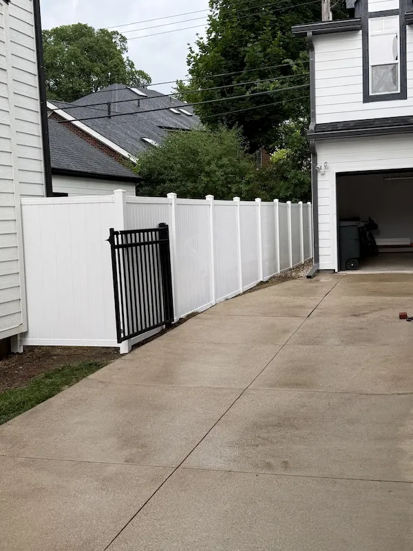 Completed white privacy fence with a black metal gate
