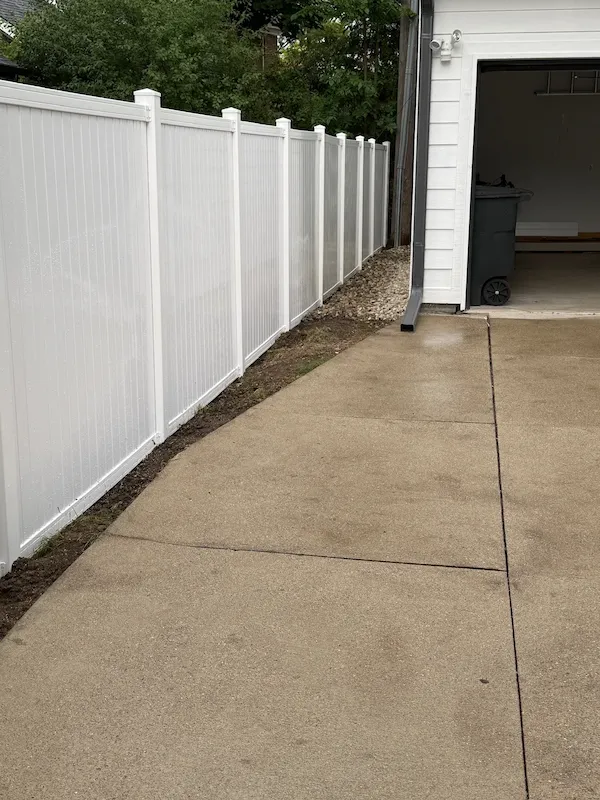 Long white vinyl fence beside a residential driveway