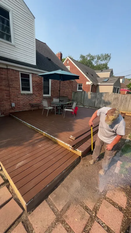 Contractor measuring boards during a composite deck installation