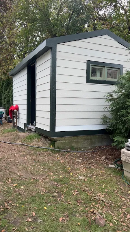 Finished backyard shed with light siding and dark trim