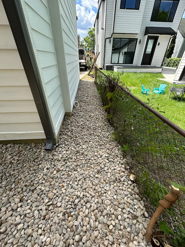Gravel drainage bed and downspout beside a home